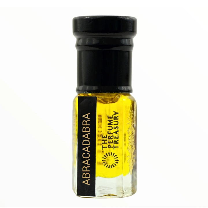 Close-up macro of Abracadabra attar perfume oil sample bottle by The Perfume Treasury, showing bright golden oil texture and elegant glass finish, long lasting attar perfume oil in clear glass bottle with black cap.