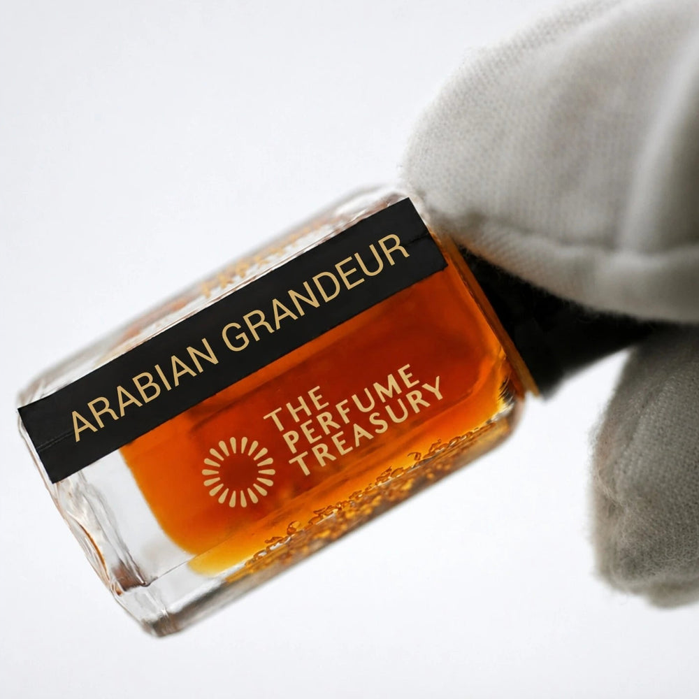 Detailed close-up image of Arabian Grandeur attar perfume bottle held in white glove, emphasizing rich amber fragrance oil, premium glass craftsmanship and elegant luxury styling.