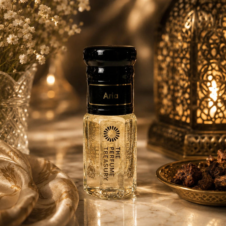 Elegant lifestyle image of Aria perfume oil bottle displayed with ornate lanterns, floral accents and warm golden lighting for a refined Arabian luxury fragrance ambiance.
