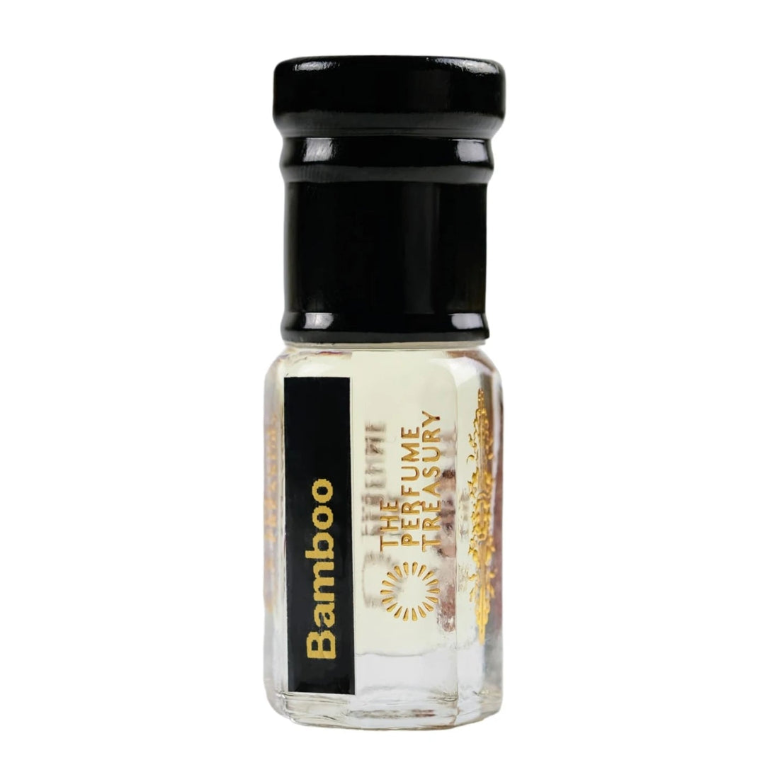 Minimal studio shot of Bamboo perfume oil by The Perfume Treasury in a sleek clear glass bottle with pale golden fragrance oil and glossy black cap on a soft white background.