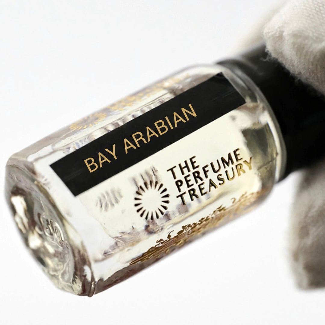 Close-up macro of Bay Arabian 3ml attar perfume oil bottle by The Perfume Treasury, showing clean transparent fragrance oil and reflective glass finish, luxury oil in clear bottle with black cap.