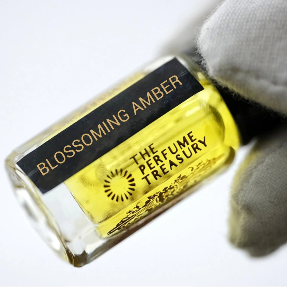 Artistic close-up of Blossoming Amber attar bottle held delicately in a white glove, highlighting the luminous fragrance oil, elegant bottle design and luxury presentation