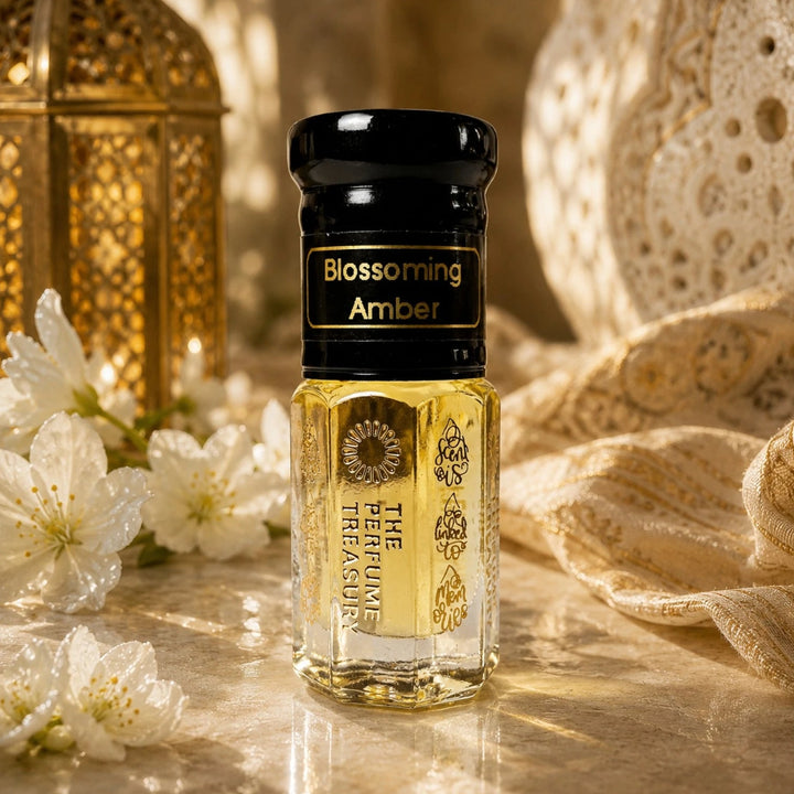 Elegant lifestyle photograph of Blossoming Amber perfume oil bottle styled with soft white flowers, warm golden lighting and luxurious textured fabrics, highlighting the rich and sophisticated fragrance presentation.