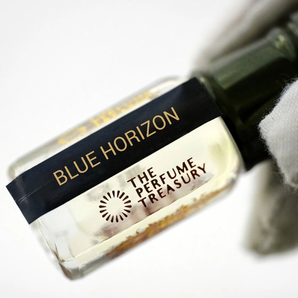 Refined close-up of Blue Horizon perfume oil bottle held in a white glove, featuring crystal-clear fragrance oil, polished glass detailing and premium black-and-gold branding