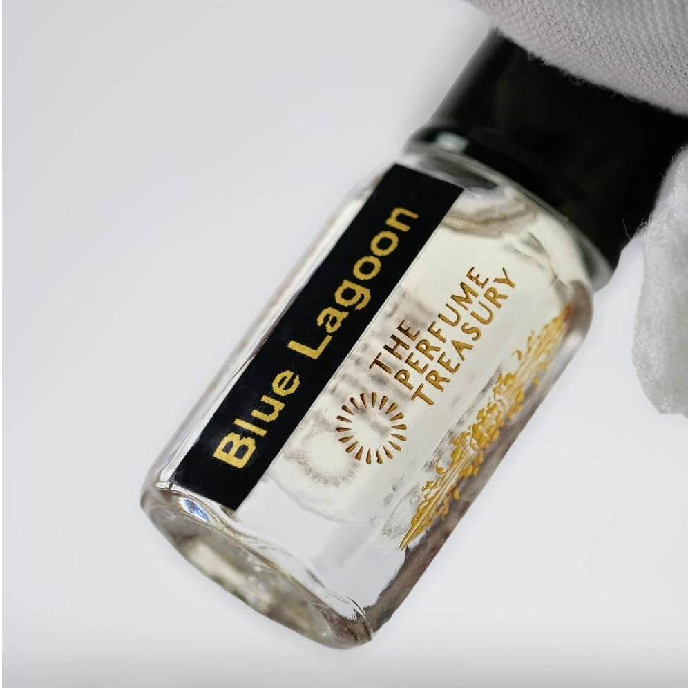 Close-up of Blue Lagoon perfume oil sample bottle held with white glove, showcasing luxury attar fragrance oil and elegant glass vial design.
