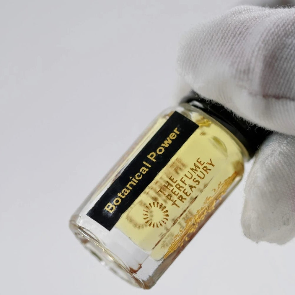 Close-up of Botanical Power perfume oil bottle held by white glove, highlighting premium fragrance oil and minimalist luxury packaging.