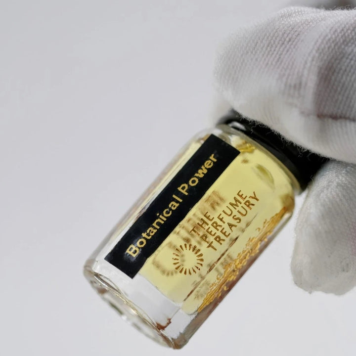 Close-up of Botanical Power perfume oil bottle held by white glove, highlighting premium fragrance oil and minimalist luxury packaging.