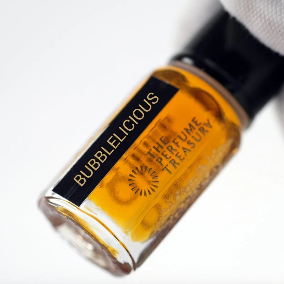 Bubblelicious attar perfume oil held in white glove, featuring vibrant amber fragrance oil in a luxury glass vial