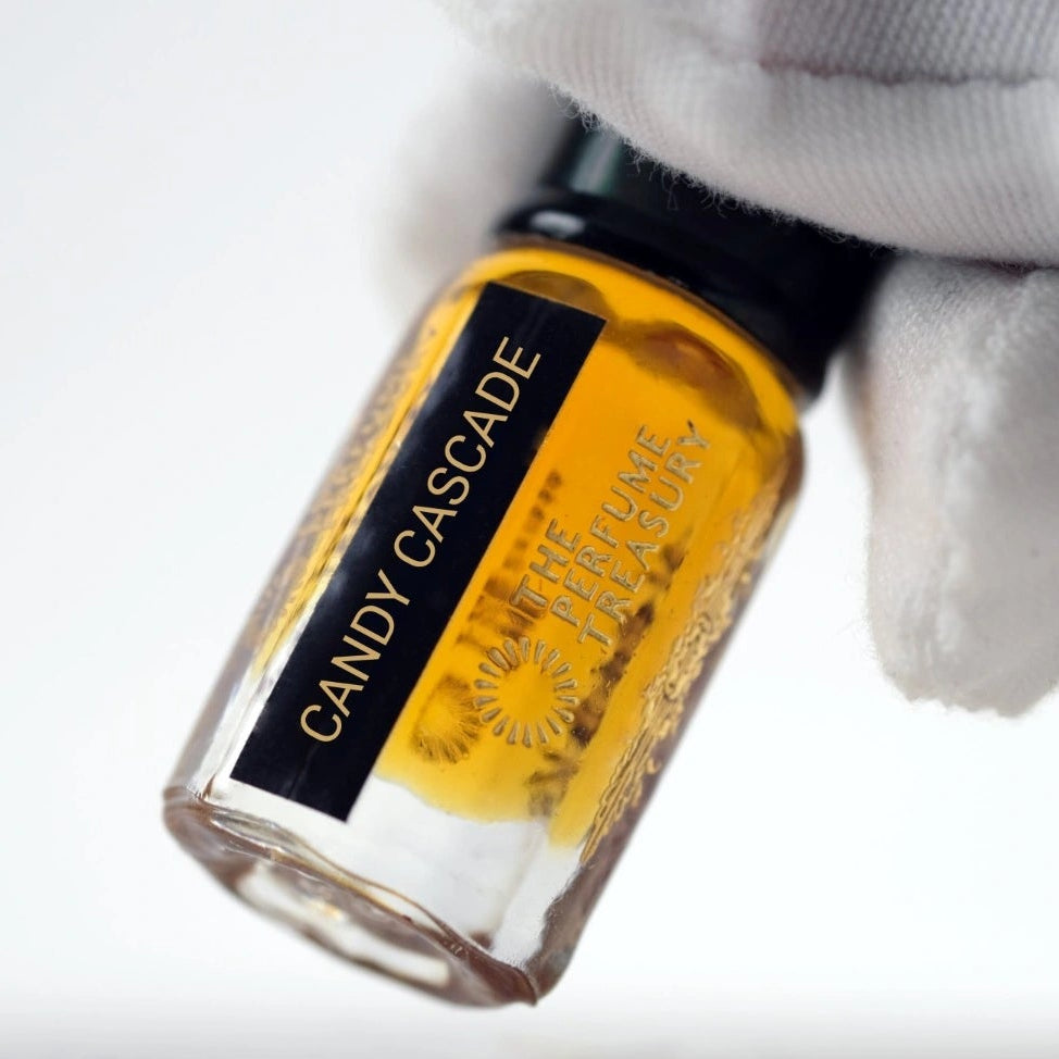 Close-up of Candy Cascade perfume oil bottle held in white glove, showcasing sweet luxury fragrance oil by The Perfume Treasury.