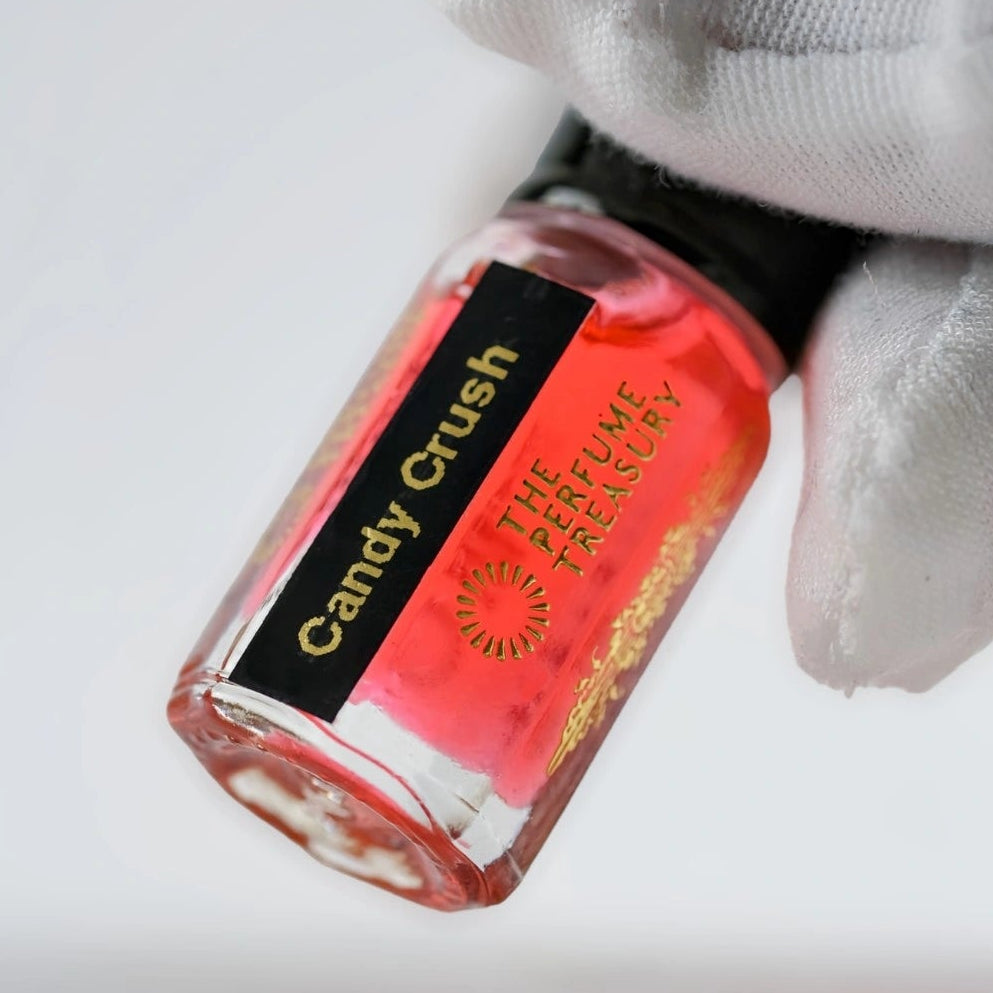 Close-up of Candy Crush musk perfume oil bottle held in white glove, showcasing vivid pink concentrated fragrance oil by The Perfume Treasury.