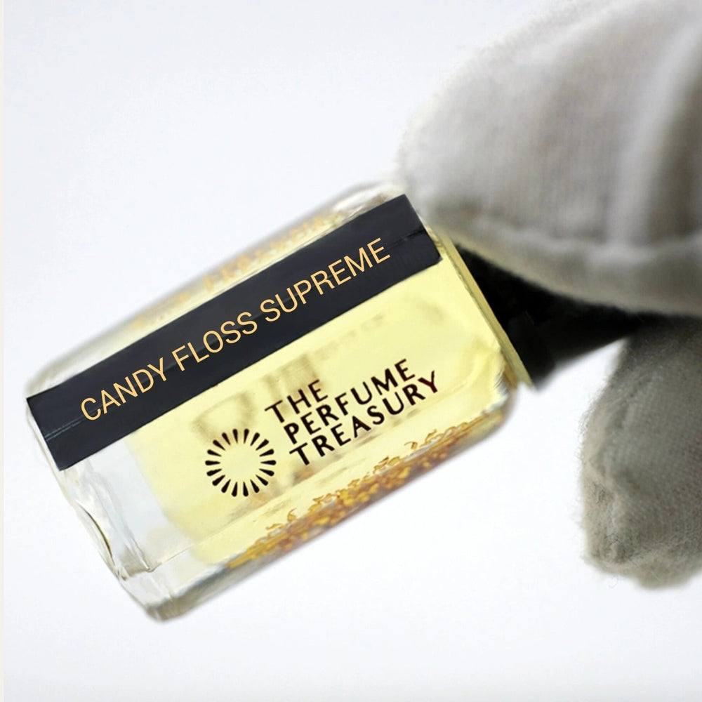 Close-up macro of Candy Floss Supreme 3ml attar perfume oil bottle held with white glove by The Perfume Treasury, showing soft pale sweet fragrance oil and glass detail, luxury perfume oil.