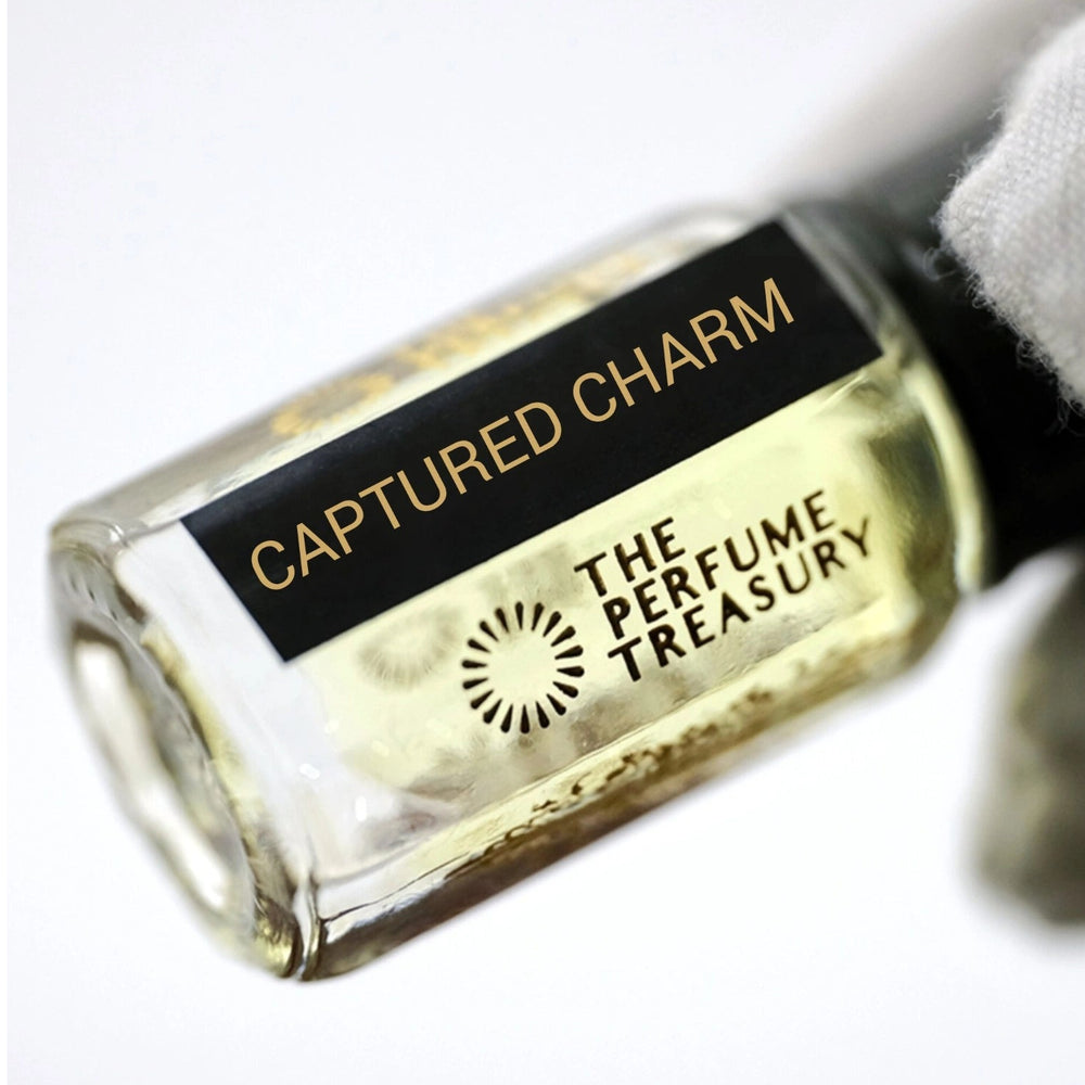 Close-up of Captured Charm perfume oil bottle held in white glove, displaying premium concentrated fragrance oil by The Perfume Treasury.