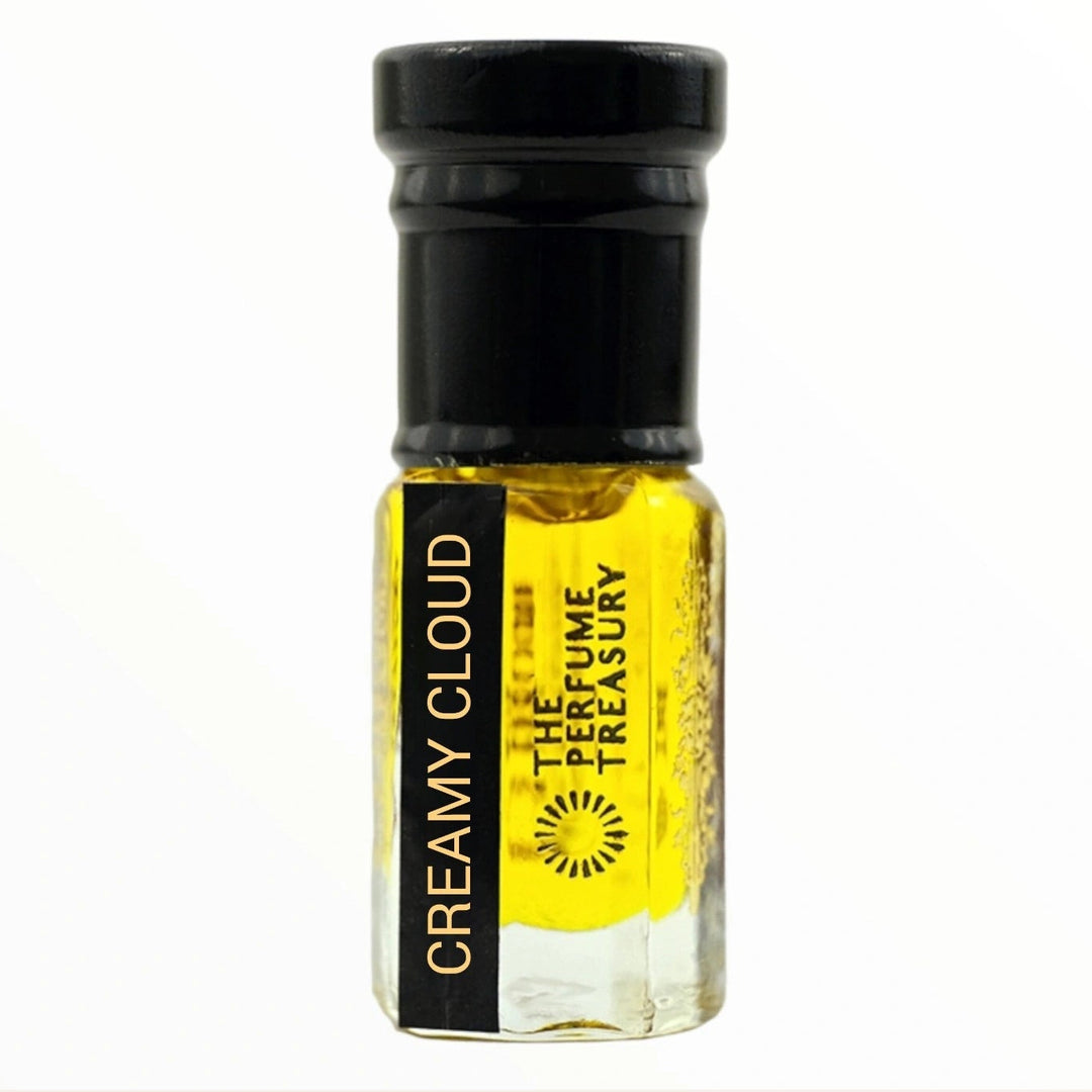 Small clear glass perfume oil bottle with black cap, Creamy Cloud 3ml attar perfume oil by The Perfume Treasury, rich bright golden fragrance oil on white background.