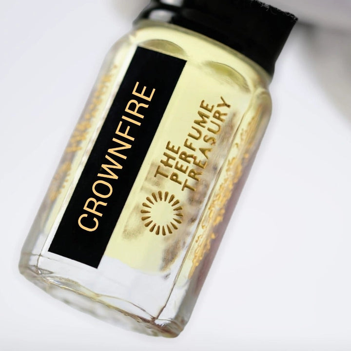 Close-up of Crownfire perfume oil by The Perfume Treasury held in hand, highlighting the premium glass bottle, concentrated fragrance oil and luxury label details.