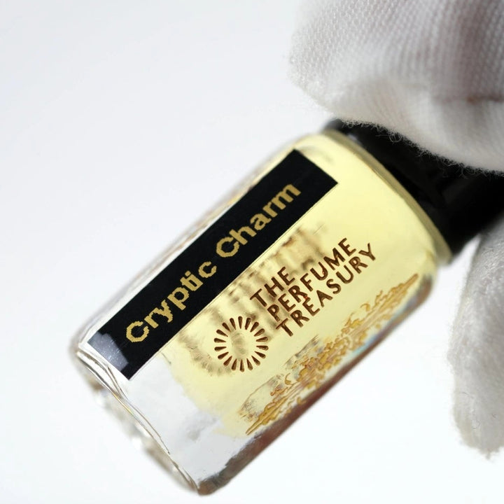 Close-up of Cryptic Charm perfume oil by The Perfume Treasury held in hand, showcasing the premium glass bottle, concentrated fragrance oil and luxury label details.