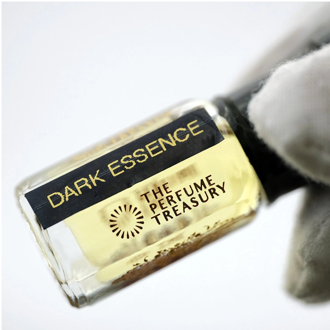 Close-up of Dark Essence perfume oil held in a white glove, showcasing The Perfume Treasury branding and premium fragrance oil presentation.