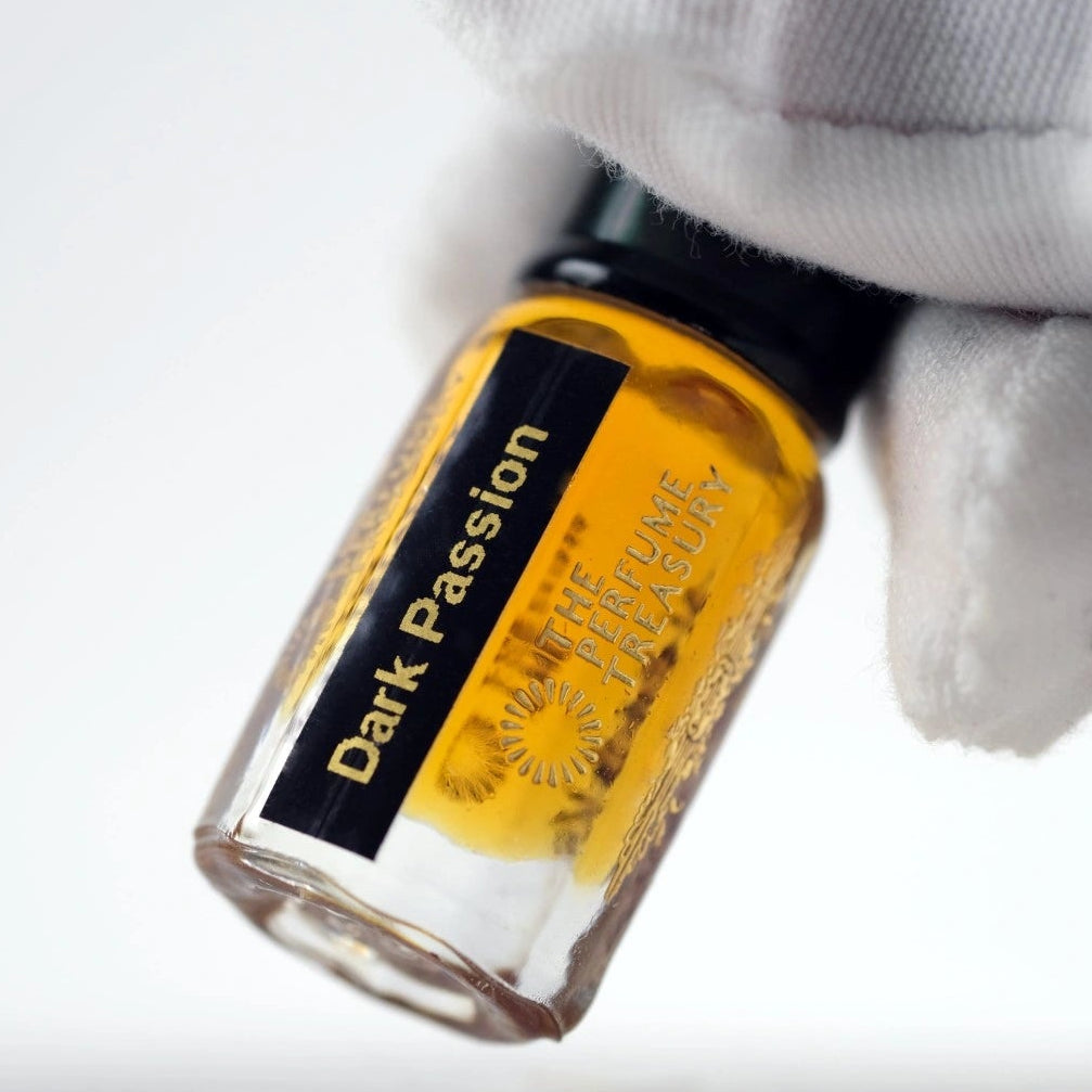 Dark Passion perfume oil held in a white glove, highlighting the rich amber oil colour and premium presentation from The Perfume Treasury.