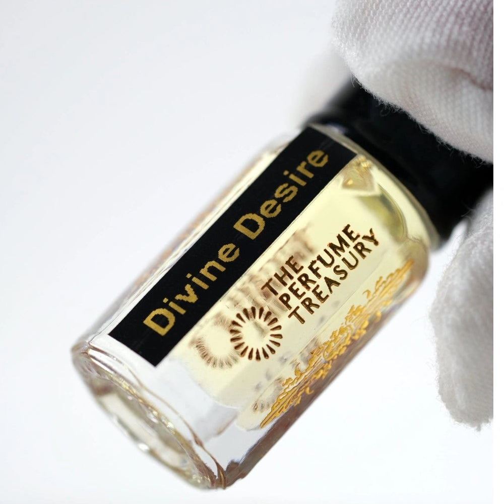 Close-up of Divine Desire attar perfume oil by The Perfume Treasury held in a white glove, showcasing the luxury bottle design and premium fragrance oil presentation.