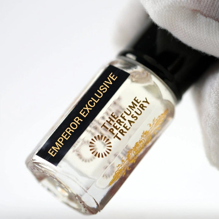 Angled close-up image of Emperor Exclusive attar perfume oil by The Perfume Treasury held in a white glove, showcasing the premium bottle design and luxury alcohol-free fragrance oil presentation.