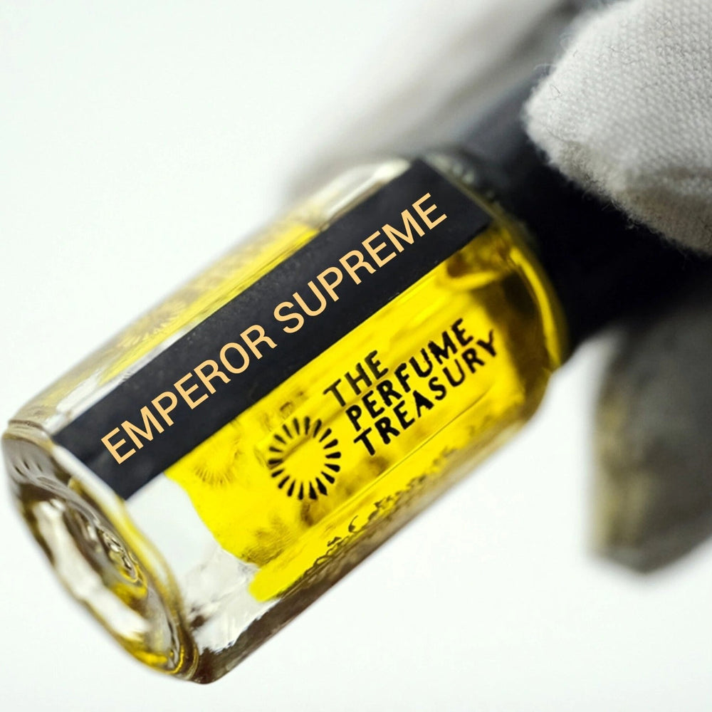 Close-up angled photograph of Emperor Supreme attar perfume oil by The Perfume Treasury held in a white glove, highlighting the vibrant golden perfume oil, luxury bottle design and alcohol-free fragrance presentation.