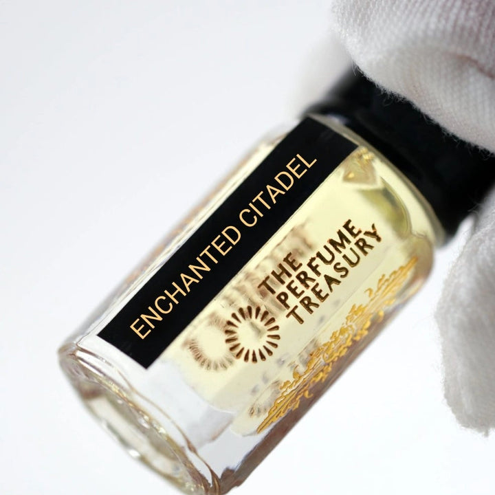 Close-up angled photograph of Enchanted Citadel attar perfume oil by The Perfume Treasury held in a white glove, showcasing the luxurious bottle design and premium alcohol-free perfume oil.