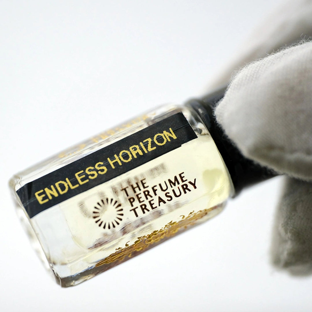 Angled close-up photograph of Endless Horizon attar perfume oil by The Perfume Treasury held in a white glove, showcasing the premium bottle design and luxury alcohol-free fragrance oil presentation.