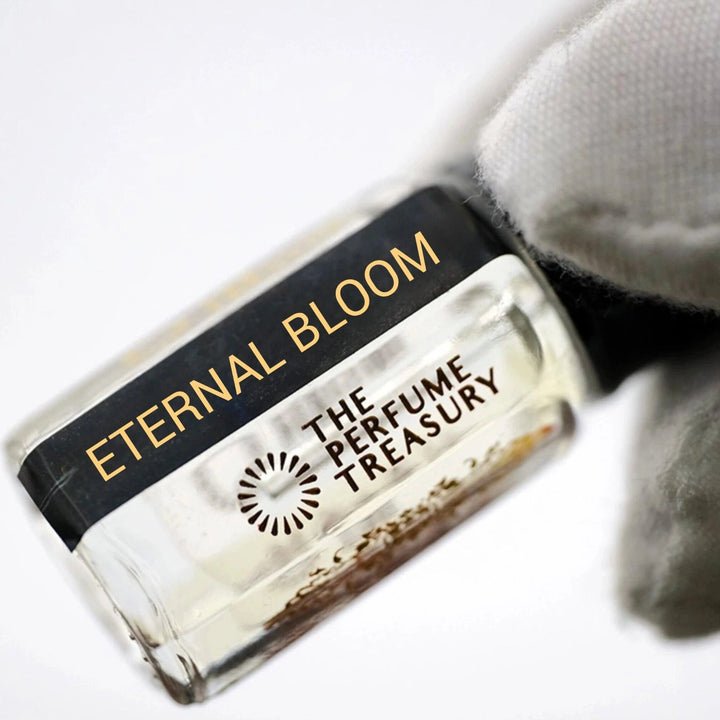 Angled close-up photograph of Eternal Bloom attar perfume oil by The Perfume Treasury held in a white glove, showcasing the premium bottle design and alcohol-free fragrance oil.