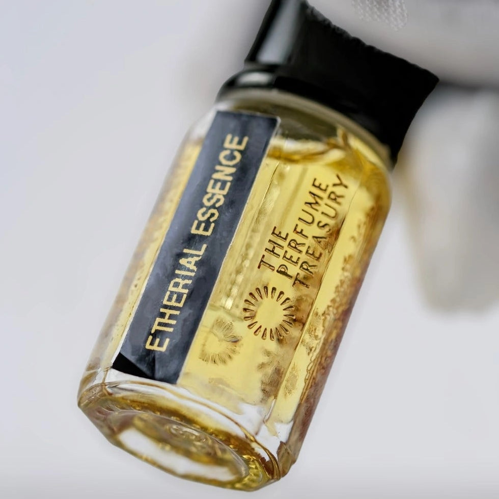Angled close-up photograph of Ethereal Essence attar perfume oil by The Perfume Treasury held in a white glove, showcasing the premium bottle design and luxury alcohol-free fragrance oil presentation.