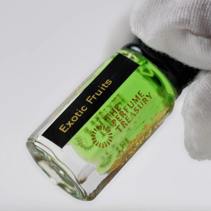 Close-up angled image of Exotic Fruits attar perfume oil by The Perfume Treasury held in a white glove, highlighting the bright green fragrance oil and premium alcohol-free perfume oil presentation.