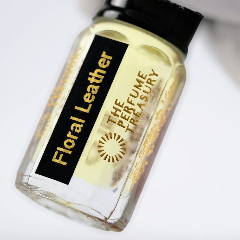 Close-up of Floral Leather attar perfume oil by The Perfume Treasury, highlighting the pale golden oil, black label and luxury glass bottle.