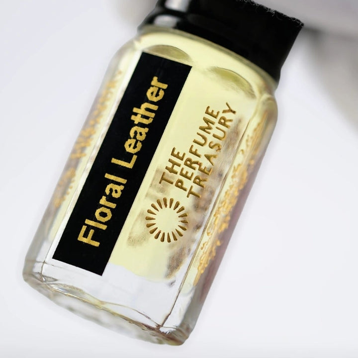 Close-up of Floral Leather attar perfume oil by The Perfume Treasury, highlighting the pale golden oil, black label and luxury glass bottle.