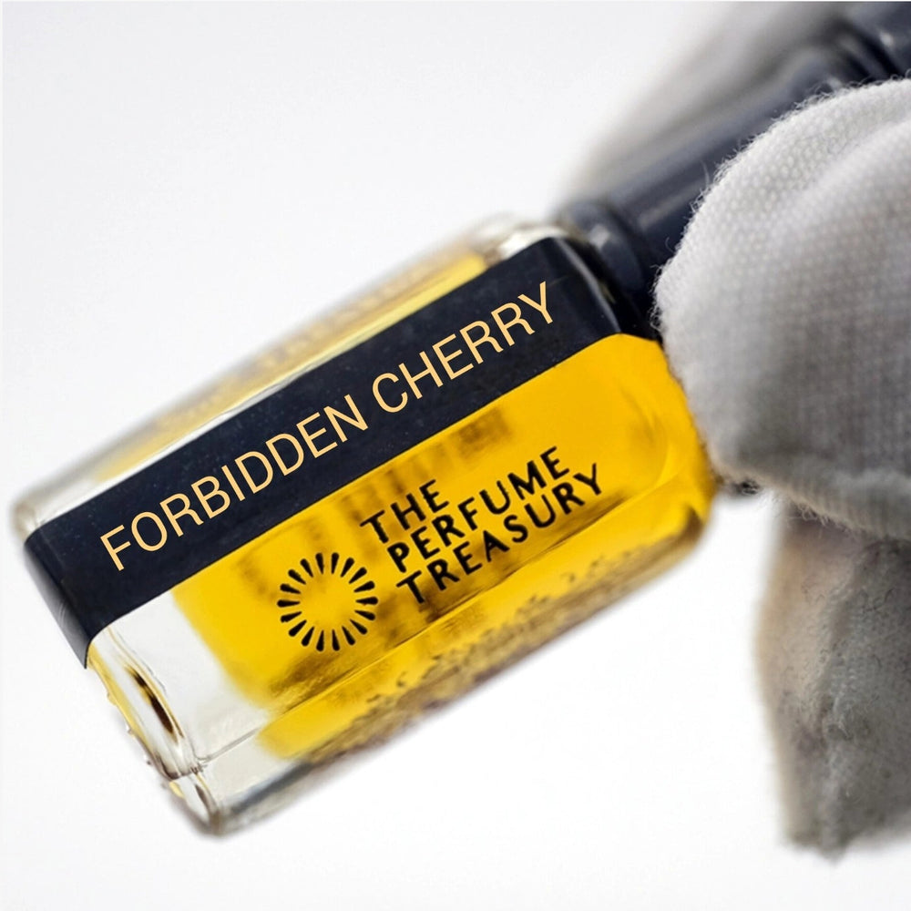 Macro close-up of Forbidden Cherry perfume oil showing vibrant golden liquid and glass reflections.
