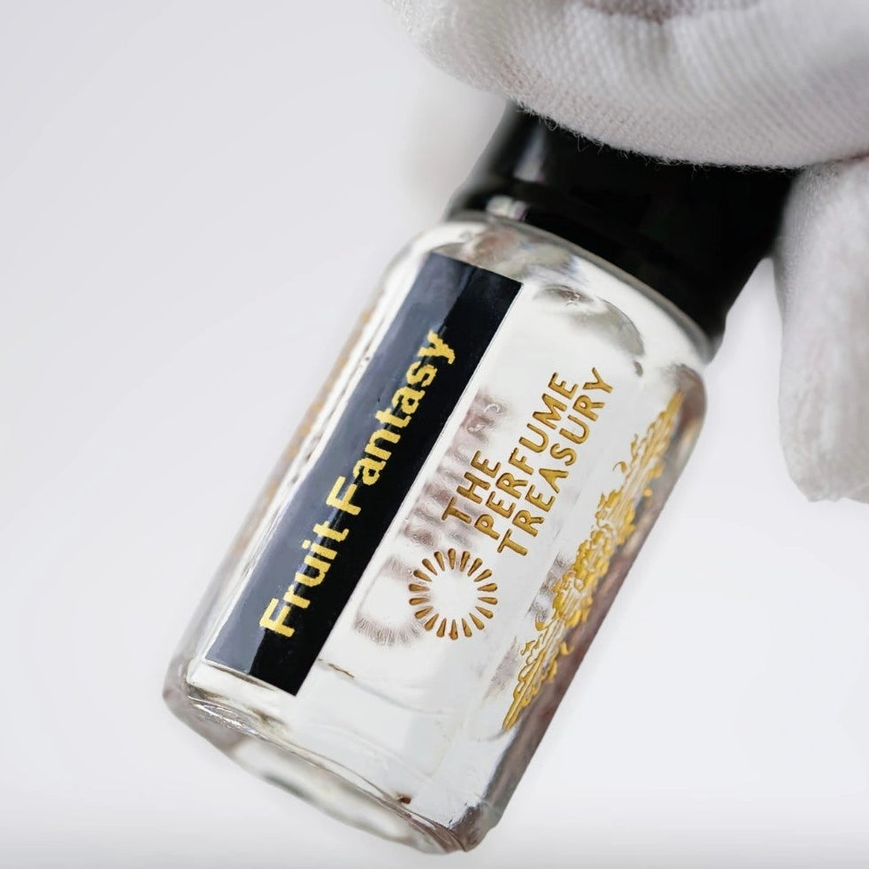 Close-up of Fruit Fantasy attar perfume oil by The Perfume Treasury, showcasing the transparent fragrance oil, black label and luxury glass bottle.
