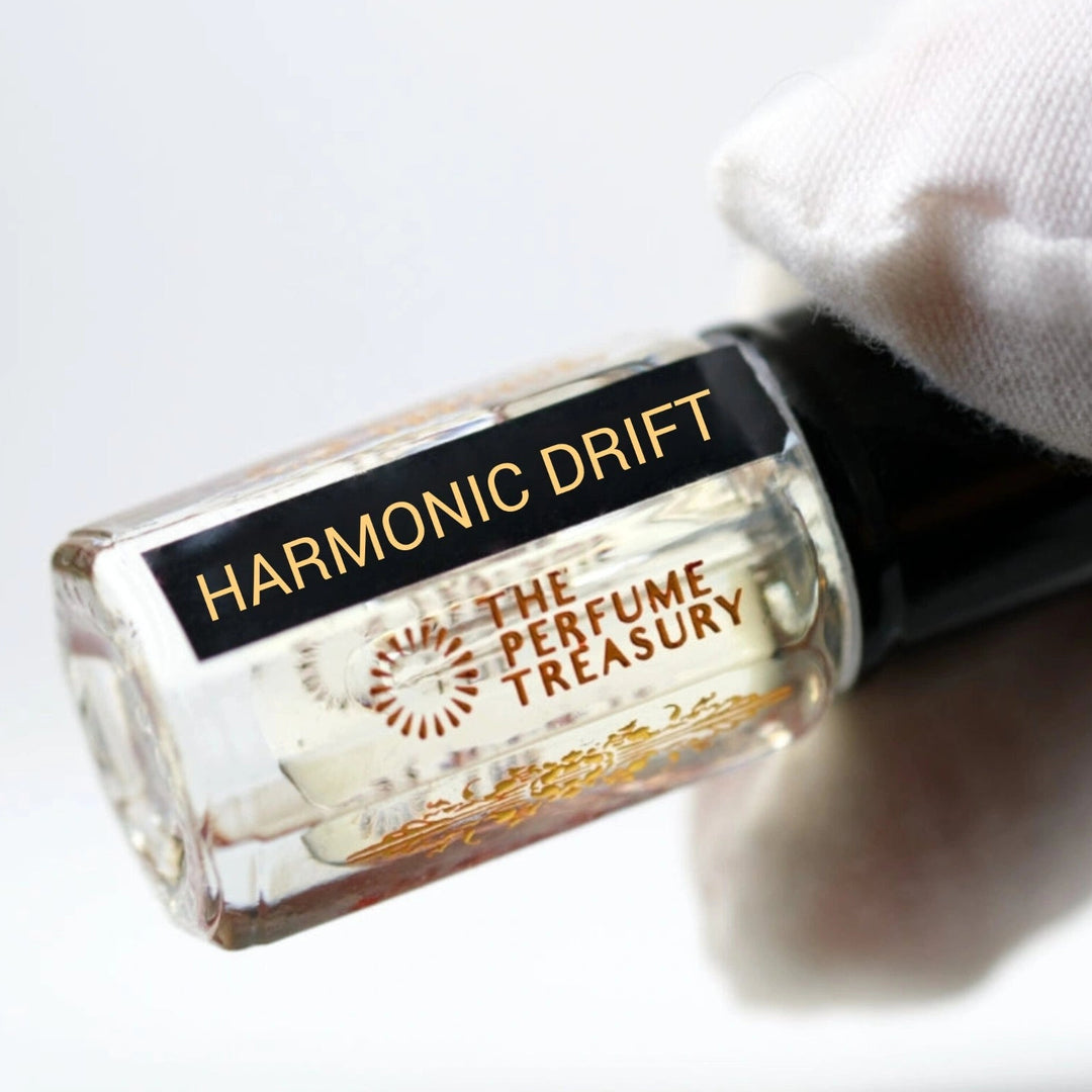 Close-up of Harmonic Drift Attar Perfume Oil by The Perfume Treasury, 3ml perfume oil bottle with black cap and label held against a soft white background.
