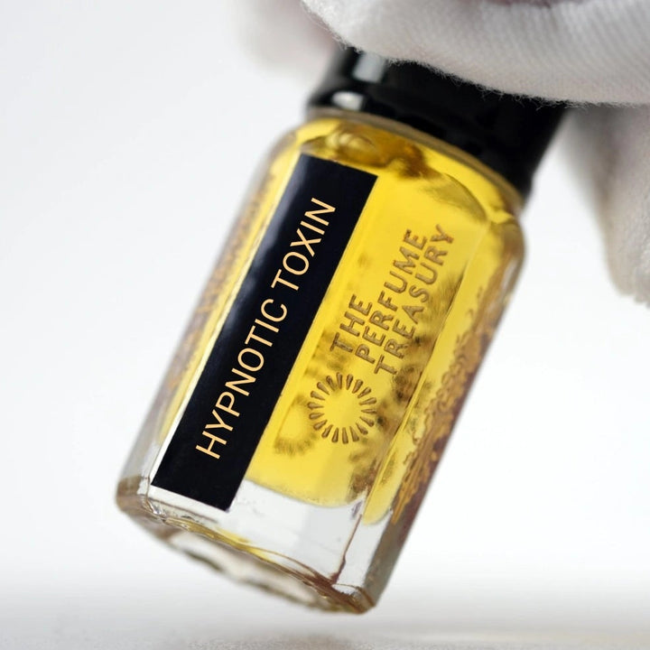 Close-up of Hypnotic Toxin Attar Perfume Oil by The Perfume Treasury, 3ml perfume oil bottle with black cap and label held against a soft white background.