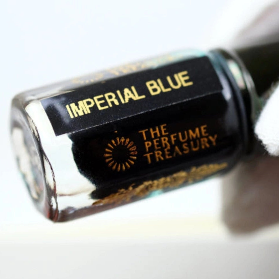 Close-up of Imperial Blue Attar Perfume Oil by The Perfume Treasury, 3ml perfume oil bottle with black cap and label held against a clean white background.