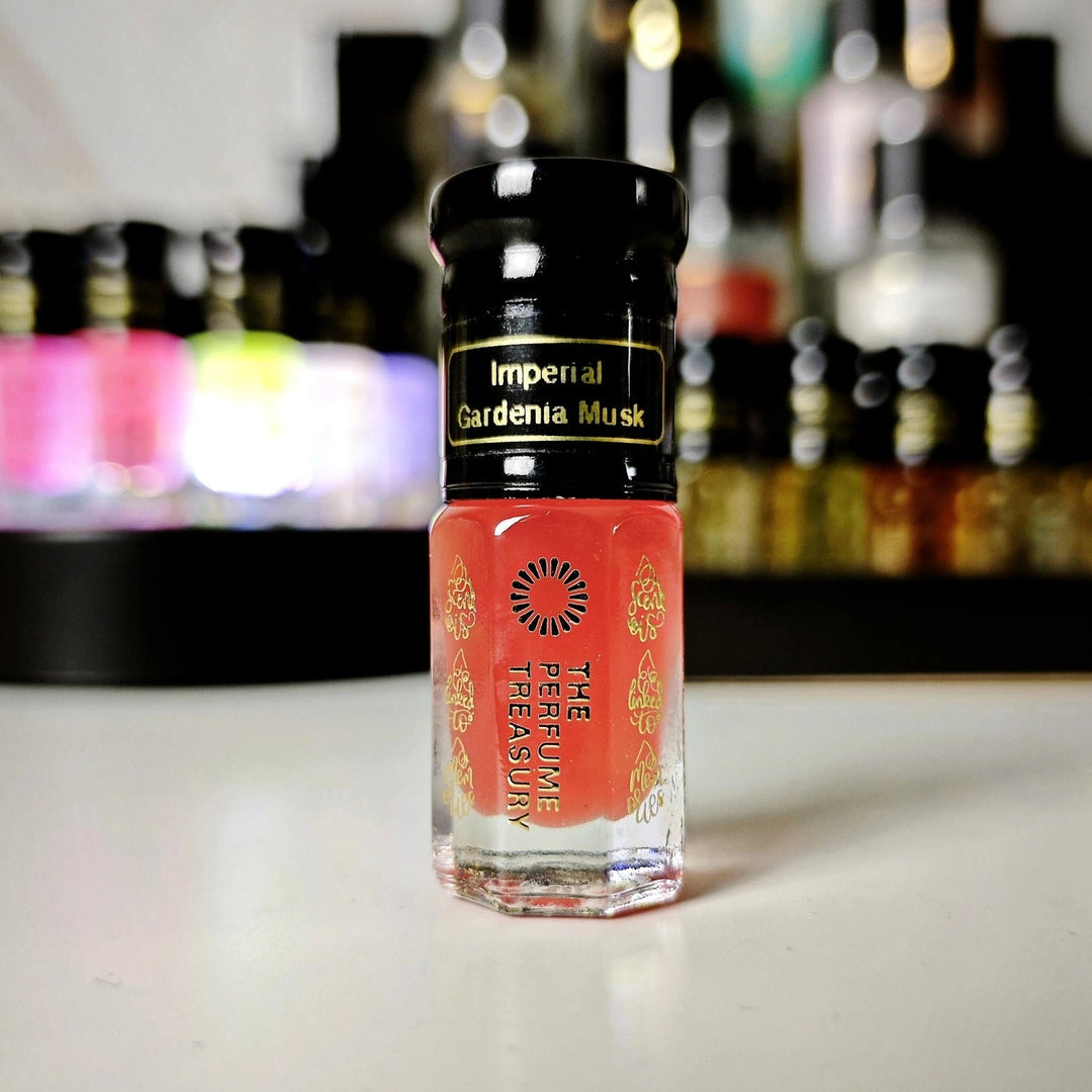 Imperial Gardenia Musk perfume oil bottle with coral pink floral musk oil and blurred fragrance collection background.
