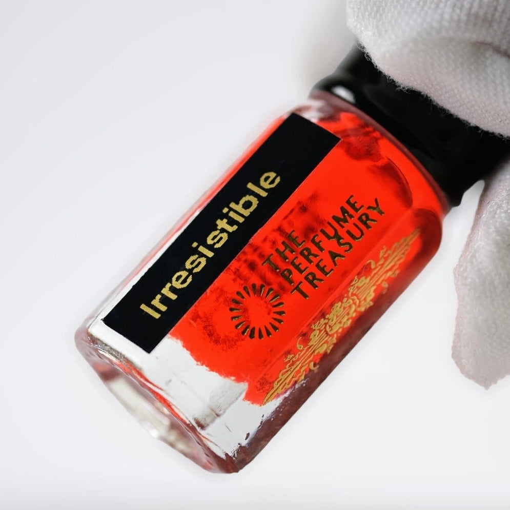 Close-up of Irresistible Perfume Oil by The Perfume Treasury, showing the vibrant red fragrance oil and branded 3ml glass bottle.