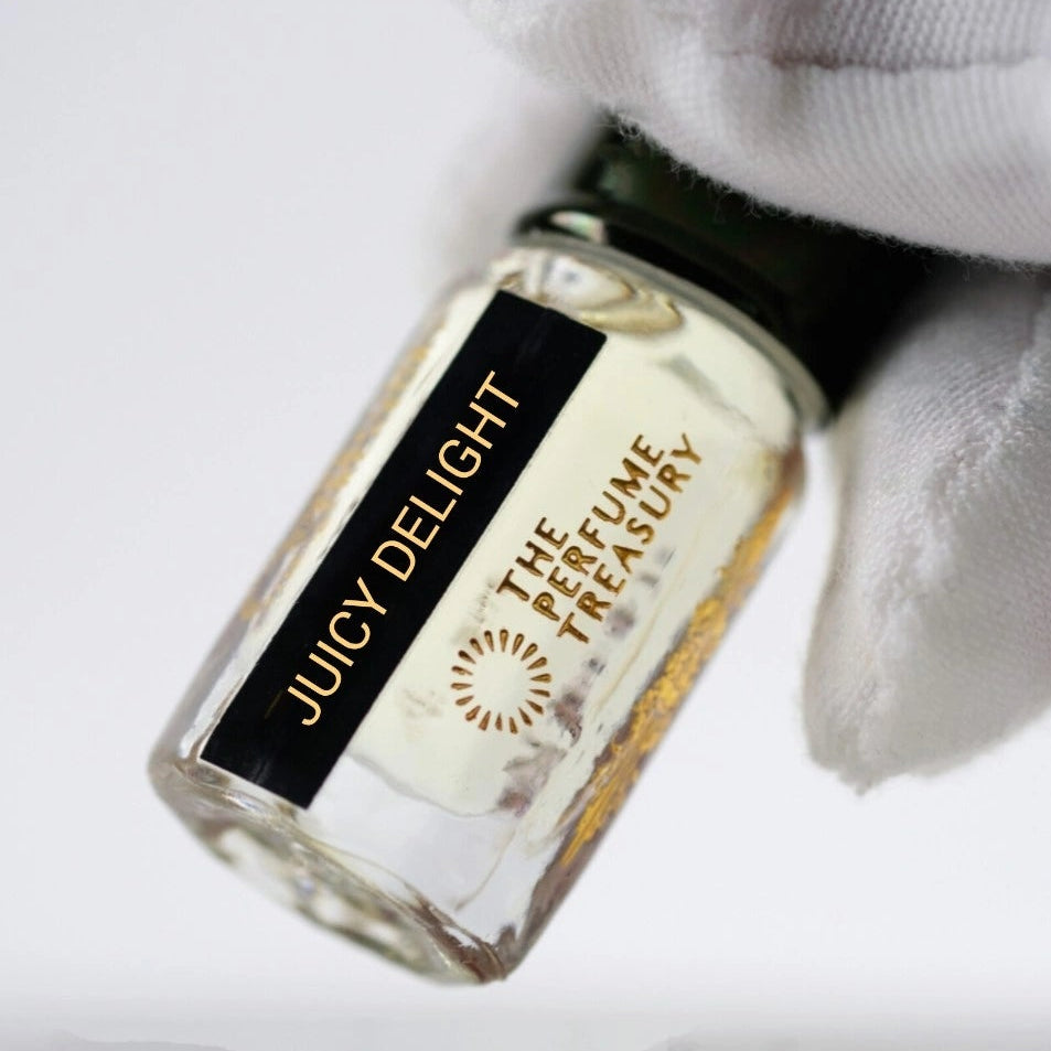Close-up of Juicy Delight Perfume Oil by The Perfume Treasury, showing the pale golden fragrance oil and branded 3ml glass bottle.