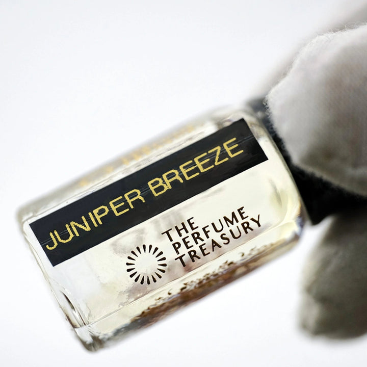 Close-up of Juniper Breeze Perfume Oil by The Perfume Treasury showing the clear fragrance oil, glass bottle and black label.