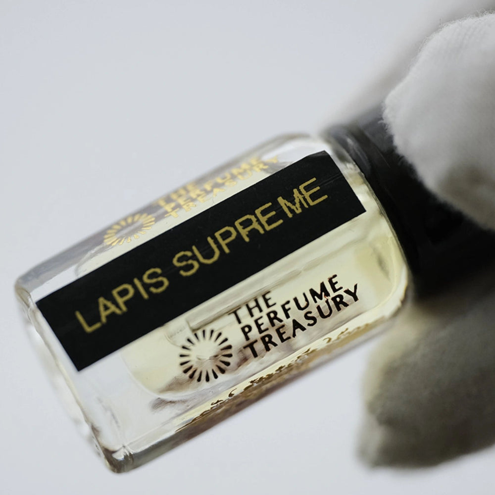 Close-up of Lapis Supreme Perfume Oil by The Perfume Treasury showing the glass attar bottle, pale fragrance oil and black label.