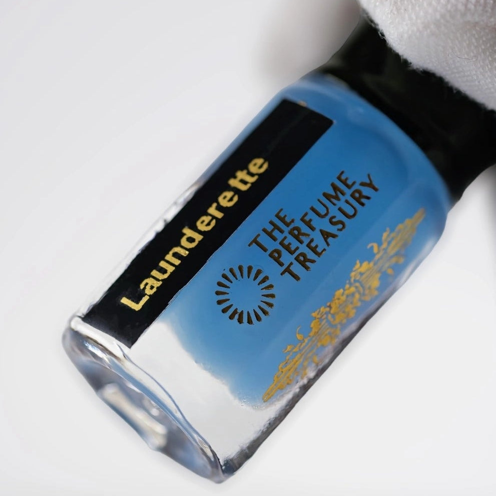 Close-up of Launderette musk tahara perfume oil bottle held with white glove, fresh clean linen body musk fragrance by The Perfume Treasury.