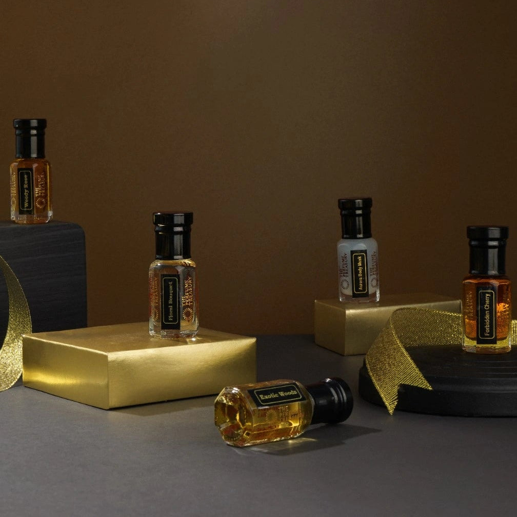 Luxury perfume oil collection by The Perfume Treasury displayed on gold blocks with ribbon in a dark premium setting.