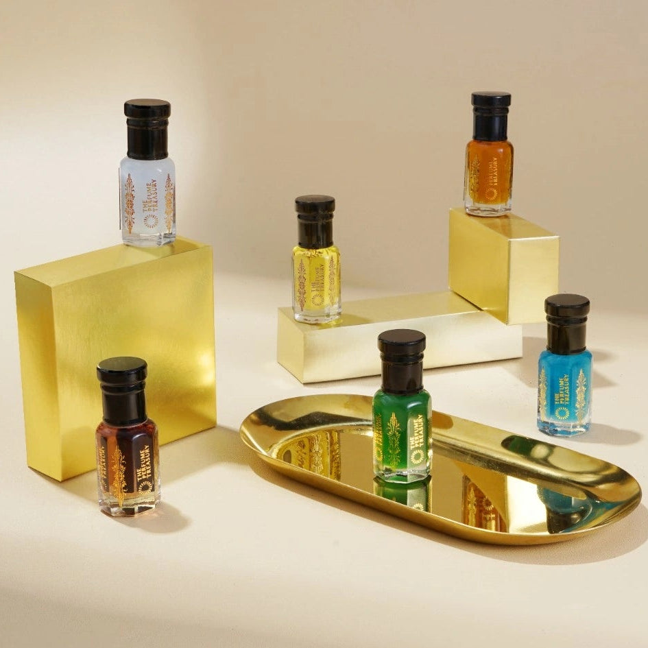 Perfume oil collection displayed on gold blocks with reflective tray, showcasing luxury fragrance presentation.