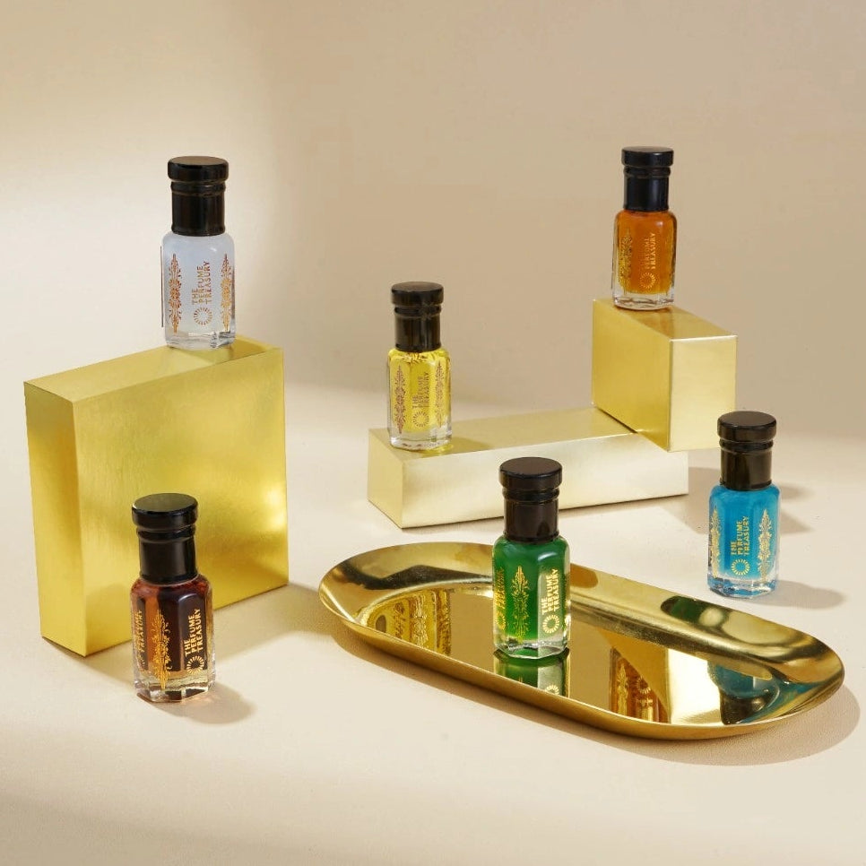 Perfume oil collection displayed on gold blocks with reflective tray, showcasing luxury fragrance presentation.