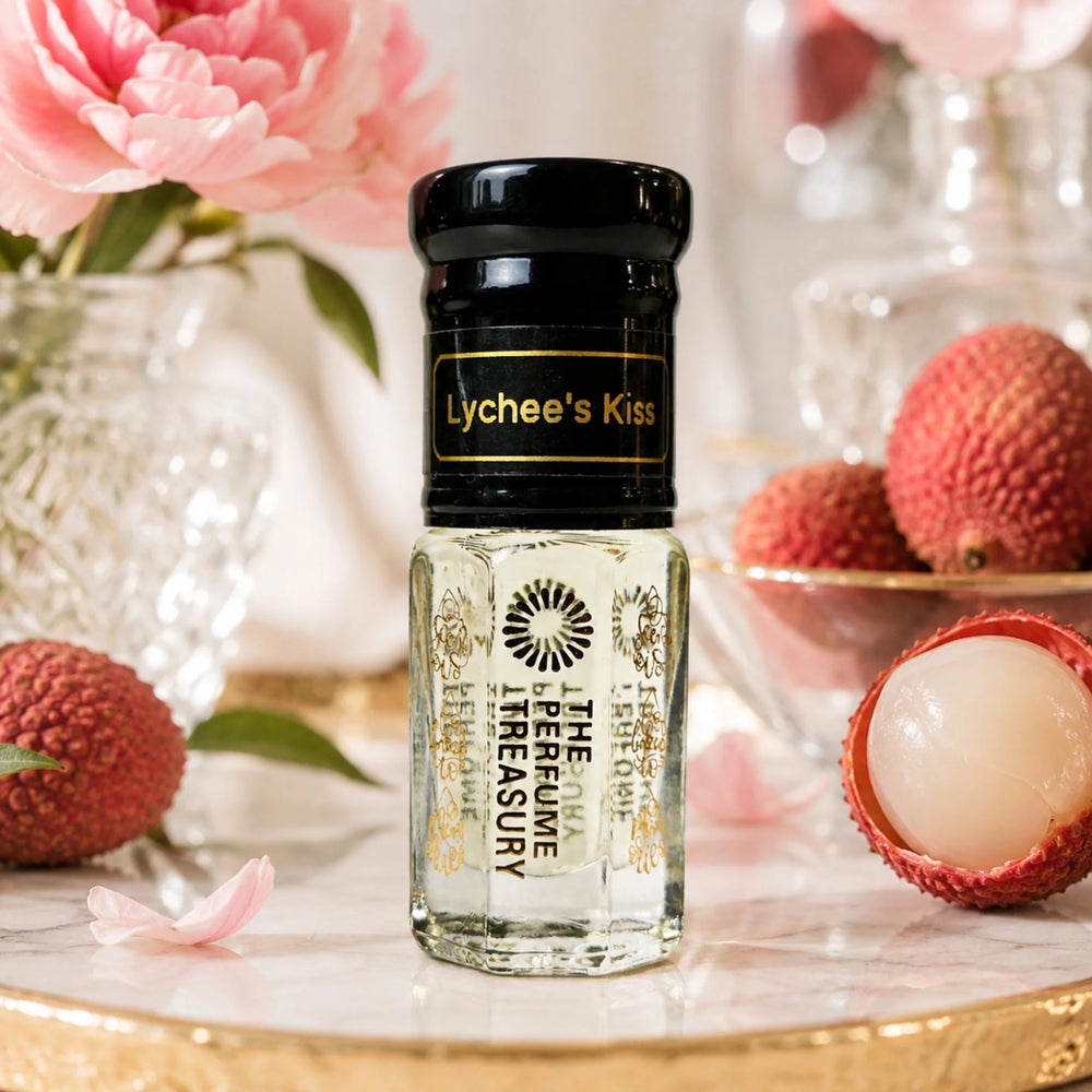 Lychee's Kiss perfume oil by The Perfume Treasury displayed with fresh lychees, pink flowers and elegant glassware in a luxurious feminine setting.