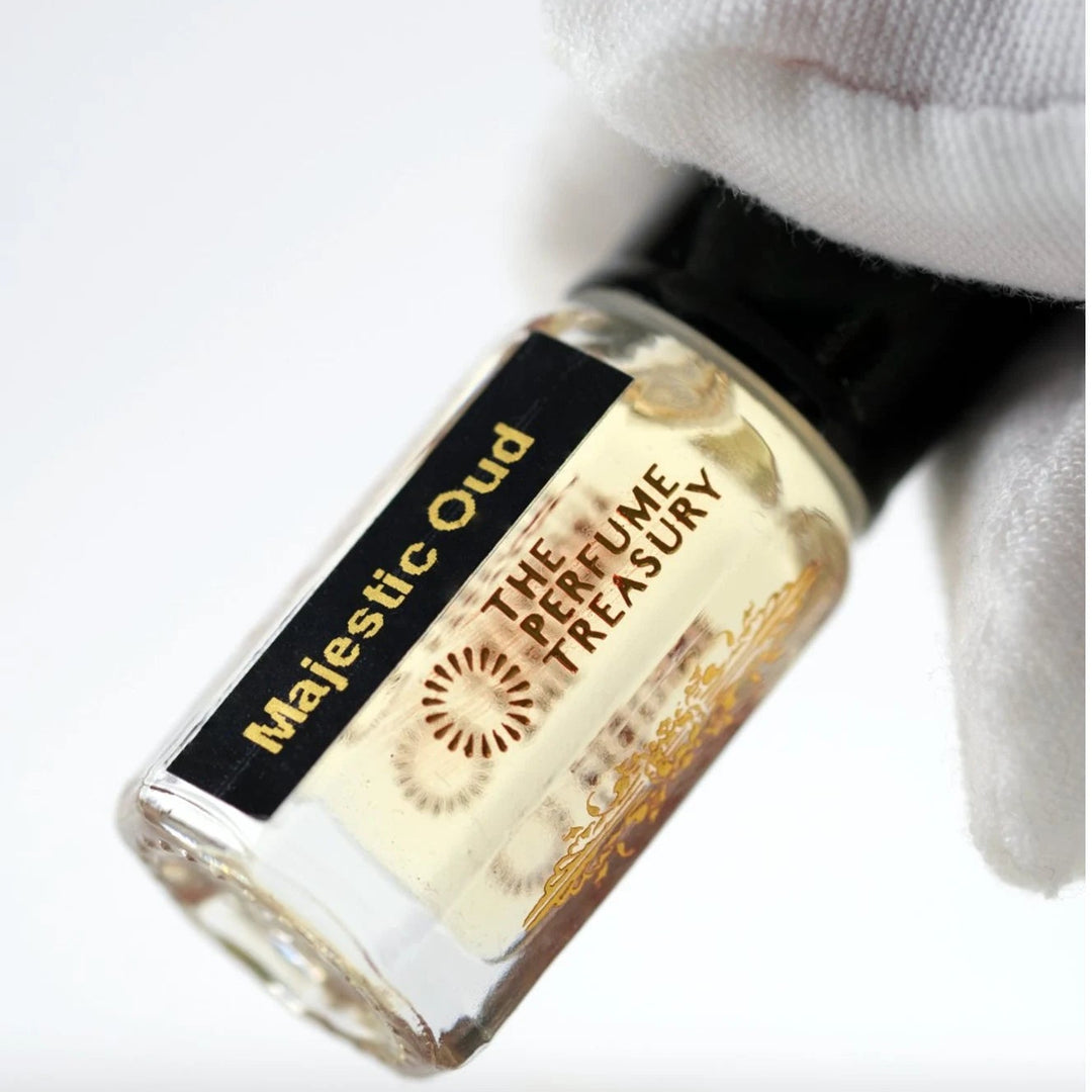 Close-up of Majestic Oud perfume oil bottle by The Perfume Treasury showing the black and gold label and pale golden fragrance oil.
