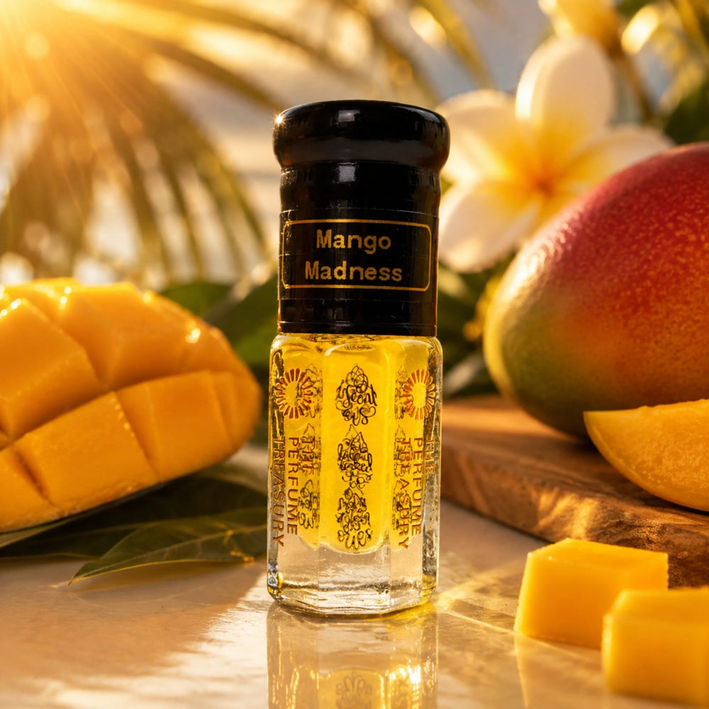 Mango Madness perfume oil by The Perfume Treasury displayed with ripe mango, sliced mango pieces and tropical foliage in a warm sunlit setting.