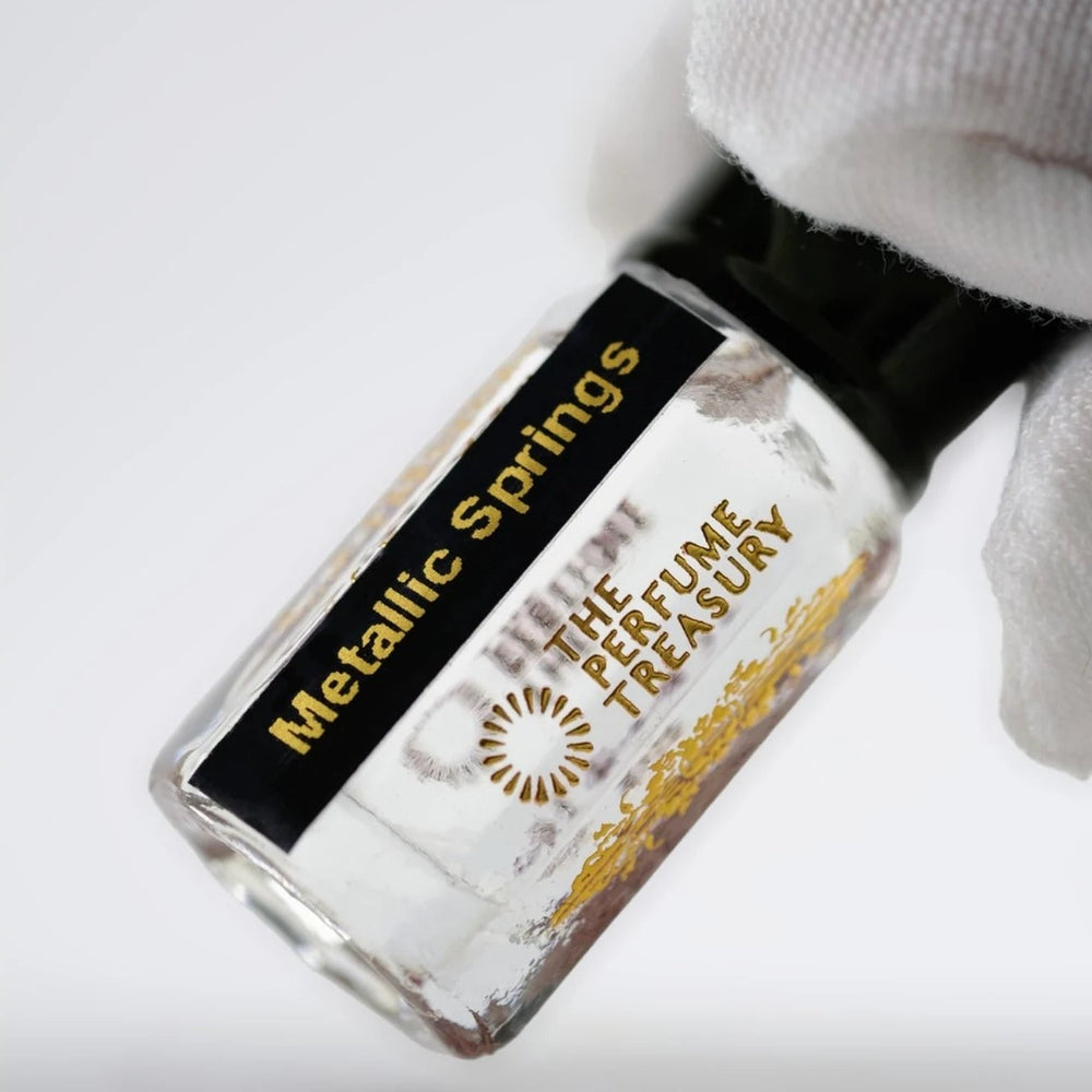 Close-up of Metallic Springs perfume oil by The Perfume Treasury showing the black and gold label and clear perfume oil.