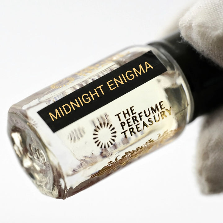 Close-up of Midnight Enigma perfume oil by The Perfume Treasury showing the black and gold label and pale fragrance oil.